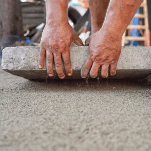 Builder sets heavy concrete slab on gravel base before starting to polish concrete surface