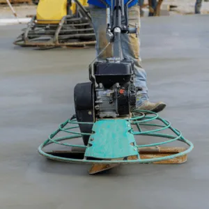 Worker operates machine to polish concrete floor after curing, creating a strong, shiny finish