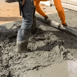 Freshly mixed concrete being poured before workers polish concrete for surface leveling and durability