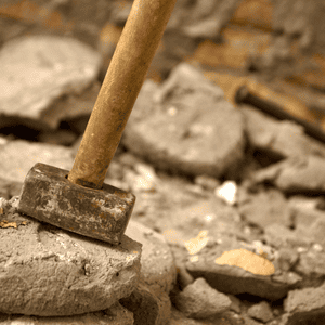 A sledgehammer rests on broken concrete after heavy-duty concrete removal in a demolition zone
