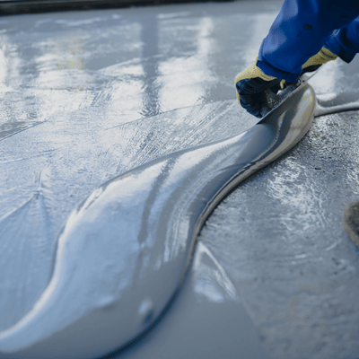 A contractor spreads self-leveling epoxy coating over the floor, comparing benefits in polished concrete vs epoxy