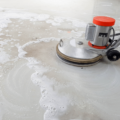 Machine scrubs a polished concrete floor with soap water during maintenance, emphasizing polished concrete vs epoxy care