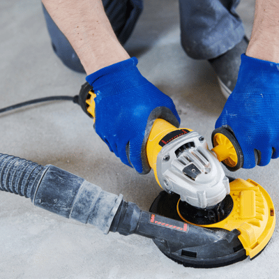 Technician uses angle grinder with dust vacuum to smooth and prep interior concrete flooring