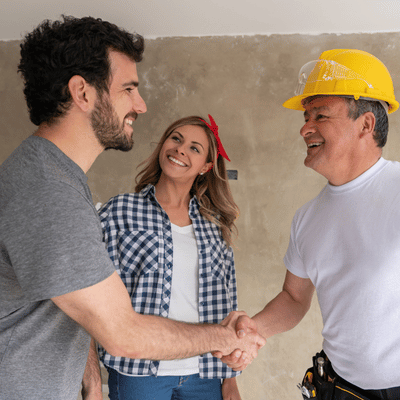 Smiling contractor shakes hands with satisfied homeowners after completing a concrete finishing job