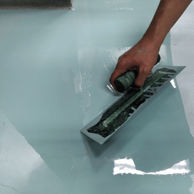 Technician trowels final epoxy coat, removing bubbles and ridges for glossy, durable finished surface appearance