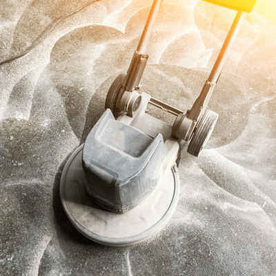 Close-up floor grinder creating swirl patterns for polished concrete in house, preparing smooth, dusted surface