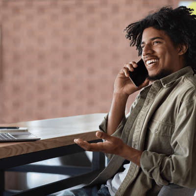 Smiling customer speaks by phone at desk, arranging service appointment and discussing project details today