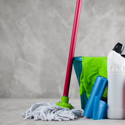 Photo shows mop, bucket, gloves, and cleaner bottles staged for professional concrete staining prep