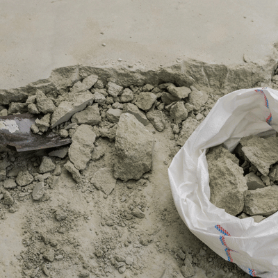 Broken concrete chunks with shovel and bag on floor, debris from concrete removal austin tx