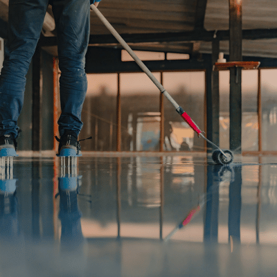 Worker rolls glossy floor coating across surface for garage floor coating fort worth installation indoors