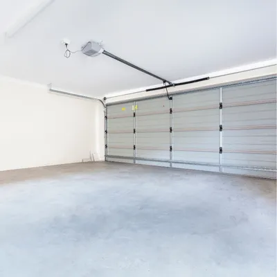 Empty garage with clean concrete slab and closed door, planning garage flooring austin upgrades