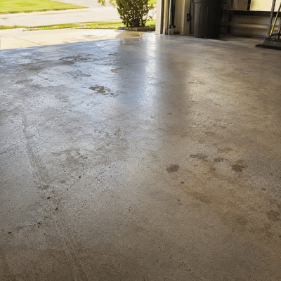 A worn concrete garage floor shows stains and cracks before an epoxy garage flooring installation