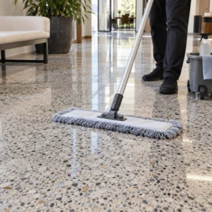 A professional uses a microfiber mop to clean and maintain a polished floor after terrazzo floor restoration in a bright interior