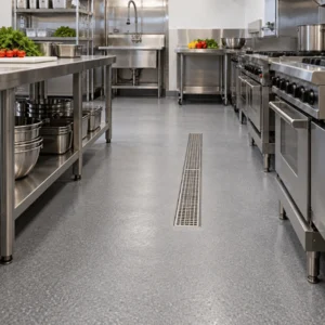 Commercial kitchen flooring provides a smooth, seamless surface with a central drain between stainless steel equipment and prep tables