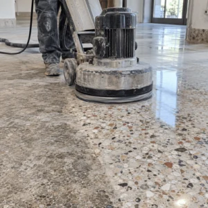 A technician operates a heavy grinding machine during terrazzo floor restoration to smooth a worn terrazzo surface and expose the aggregate